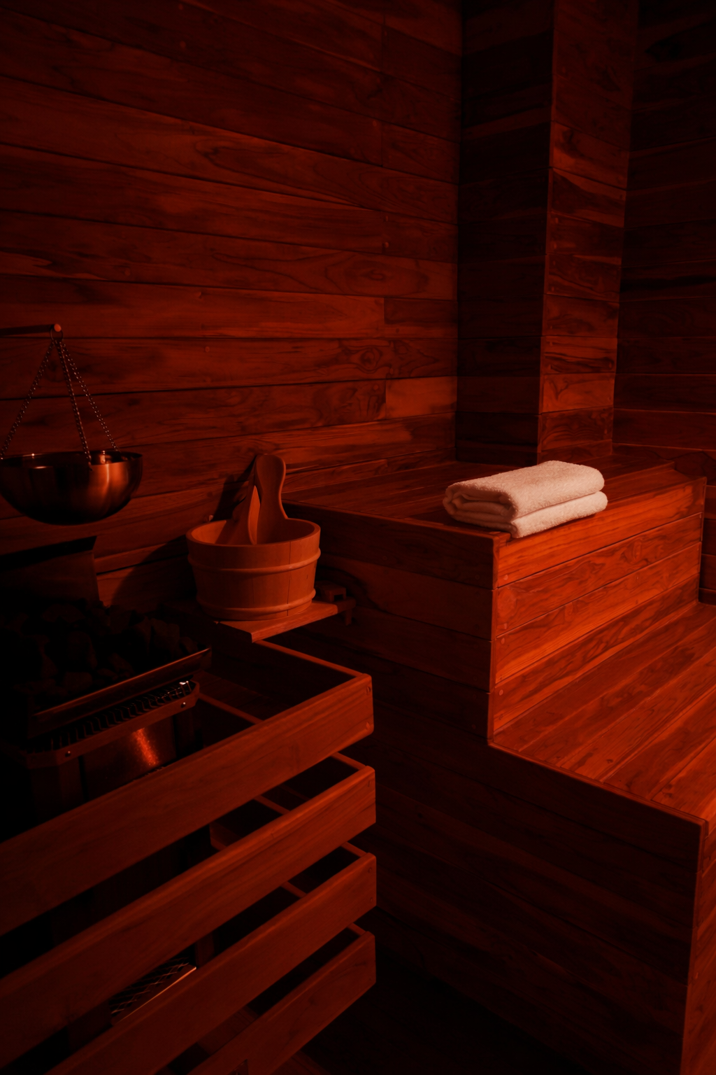 Sauna infrarrojo de madera con cubeta y toallas.