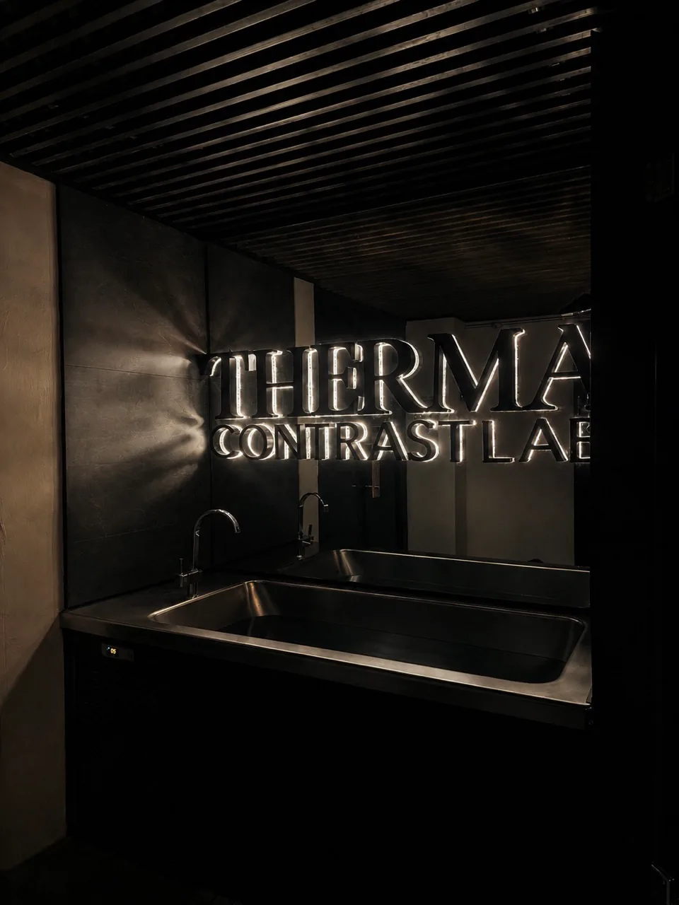 Letrero THERMÁ Contrast Lab sobre el lavabo de acero.